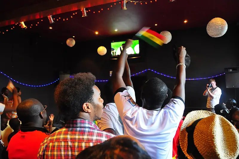 Football fans cheering while watching a televised match