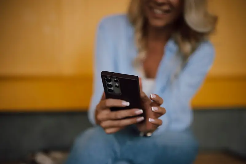 Smiling woman holding a smartphone to play a mobile game
